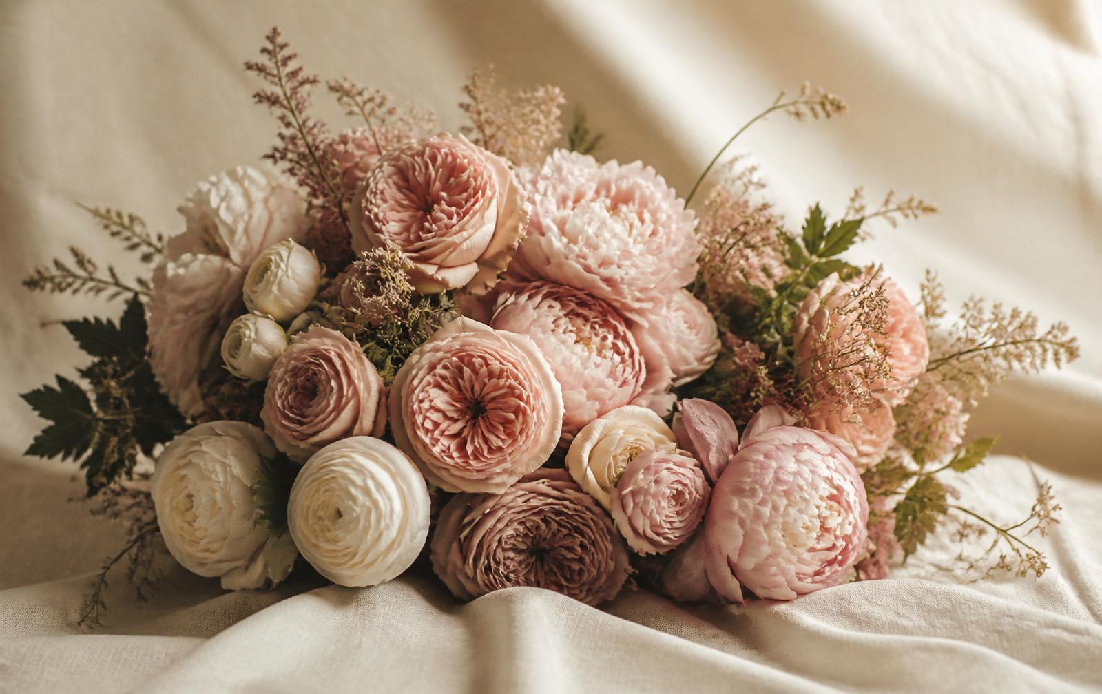 Bouquet of roses, peonies and ranunculus on linen